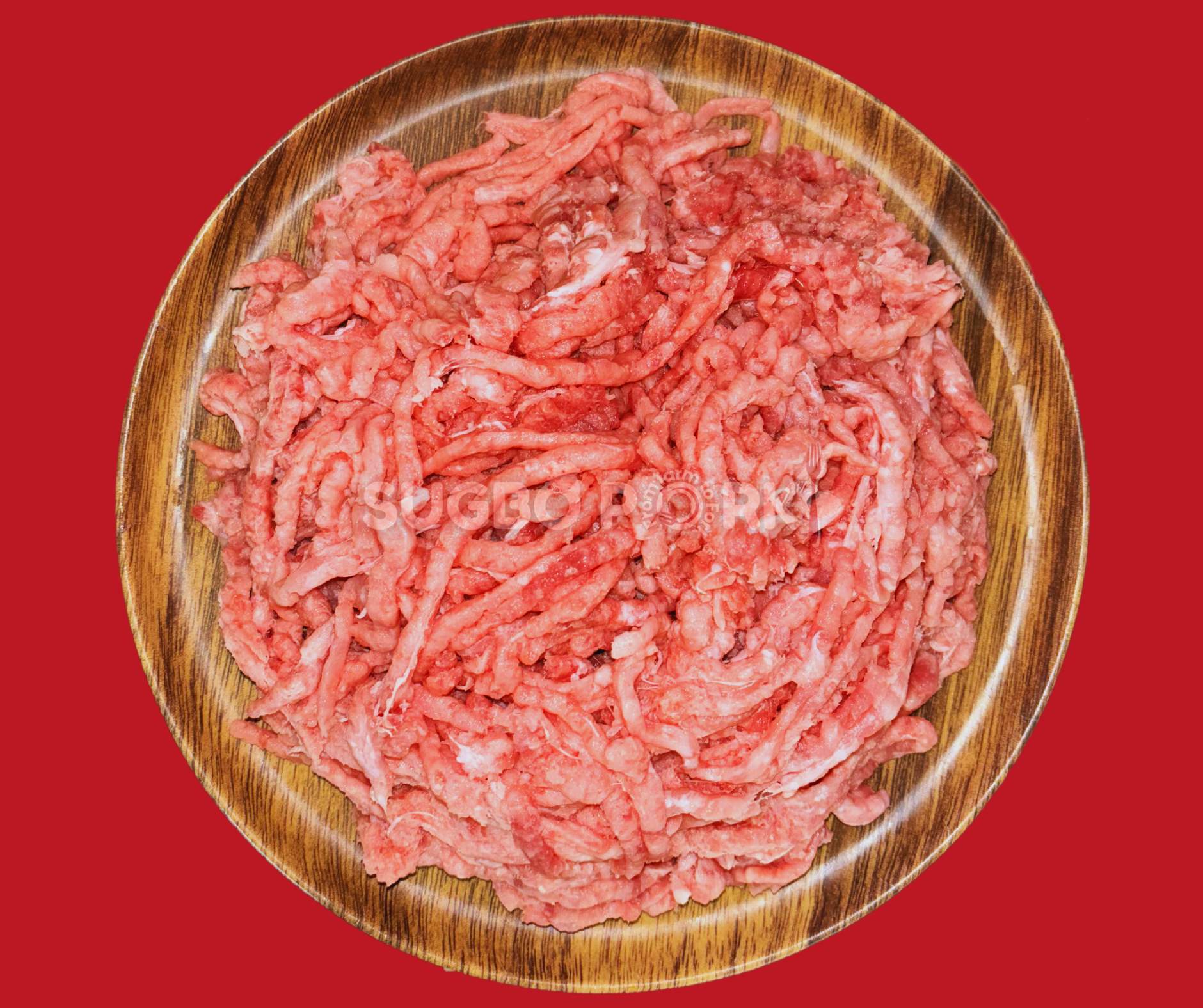 Professional product photography showing fresh ground pork in wooden circular bowl with excellent texture and color against vibrant red background featuring Sugbo Pork watermark